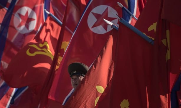 A Korean People's Army (KPA) soldier stands between flags prior to the opening ceremony for the Ryomyong Street housing development in Pyongyang on April 13, 2017.
