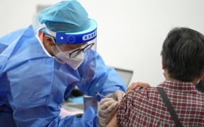 (221217) -- BEIJING, Dec. 17, 2022 (Xinhua) -- A medical worker injects a booster shot of COVID-19 vaccine for a resident at Aoyuncun Subdistrict in Chaoyang District, Beijing, capital of China, July 13, 2022. (Xinhua/Ju Huanzong) (Photo by Ju Huanzong / XINHUA / Xinhua via AFP)