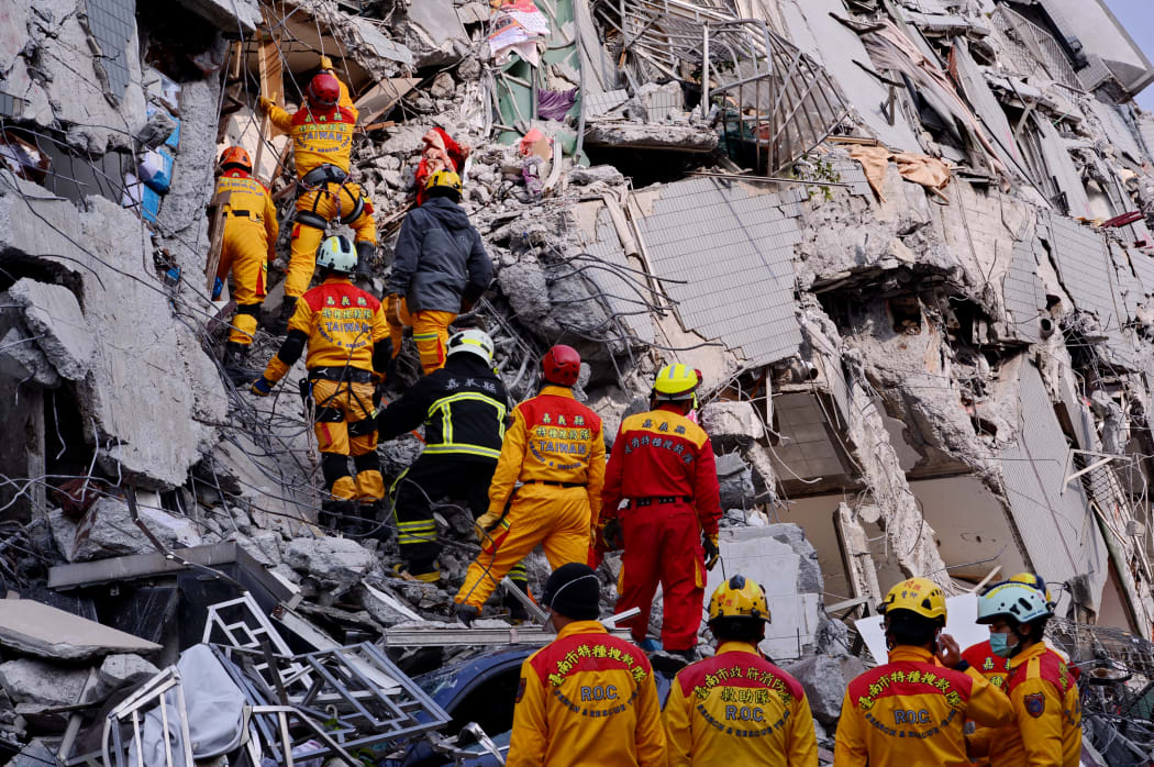 Rescuers try to look for victims at the site where a building collapsed during an earthquake in Tainan.