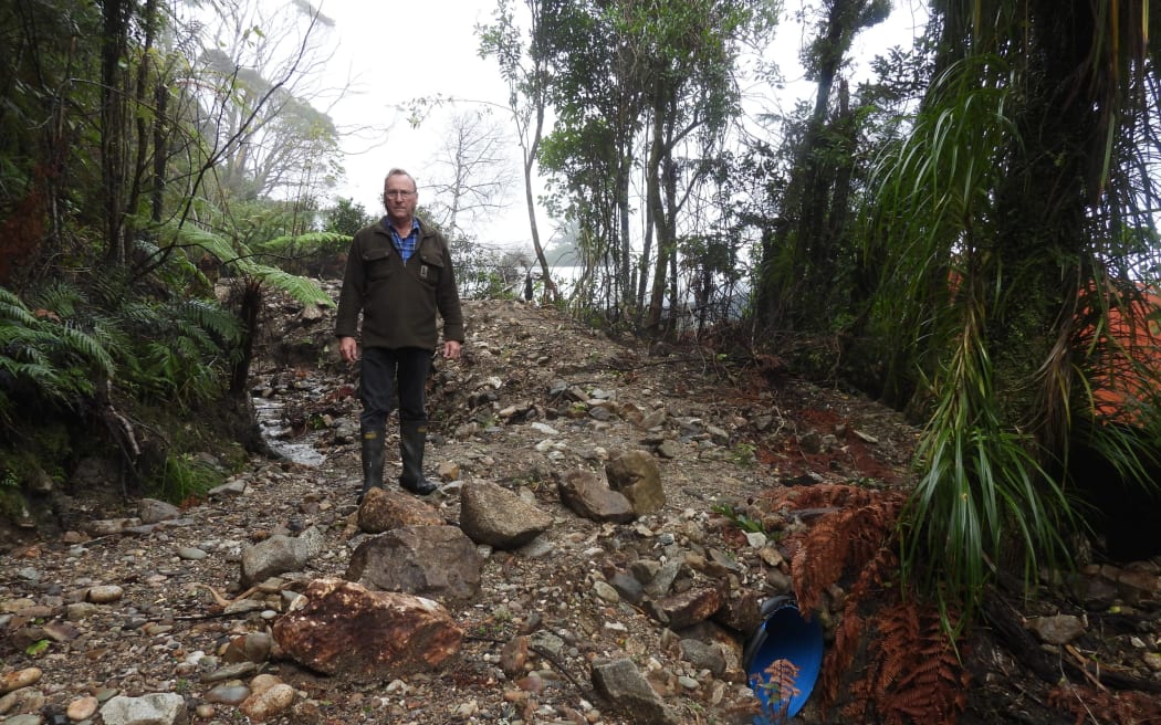 Northern Buller Museum Trust chair Derek Lord points to the culvert which blocked in February, diverting the stream to the museum buildings rear.