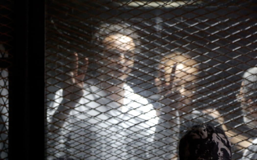 Egyptian photojournalist Mahmoud Abu Zied, known by his nickname Shawkan, gestures in a soundproof glass cage inside a makeshift courtroom in Tora prison in Cairo, Egypt