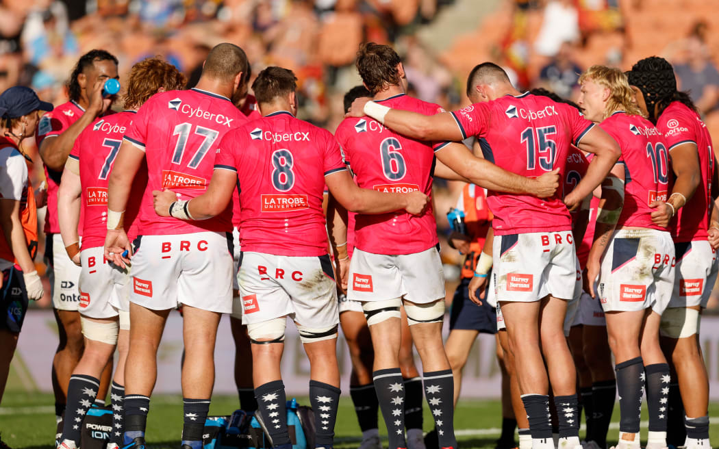 Rebels players huddle after scoring a try.