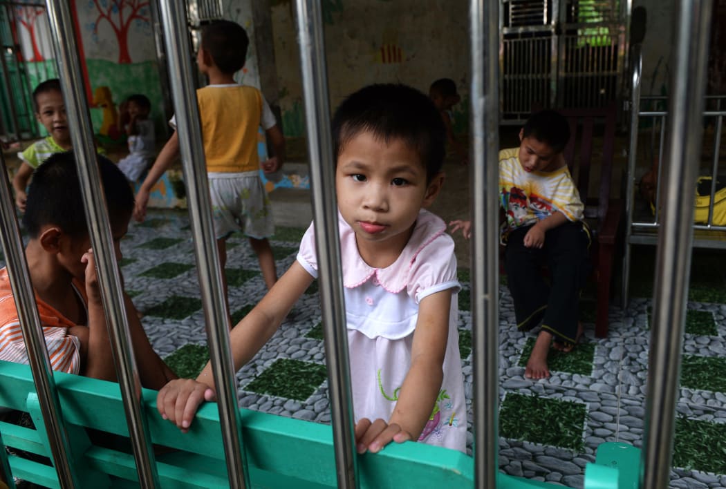 A young girl looks at visitors inside a state-run orphanage on the outskirts of Hanoi, Vietnam in September 2014.