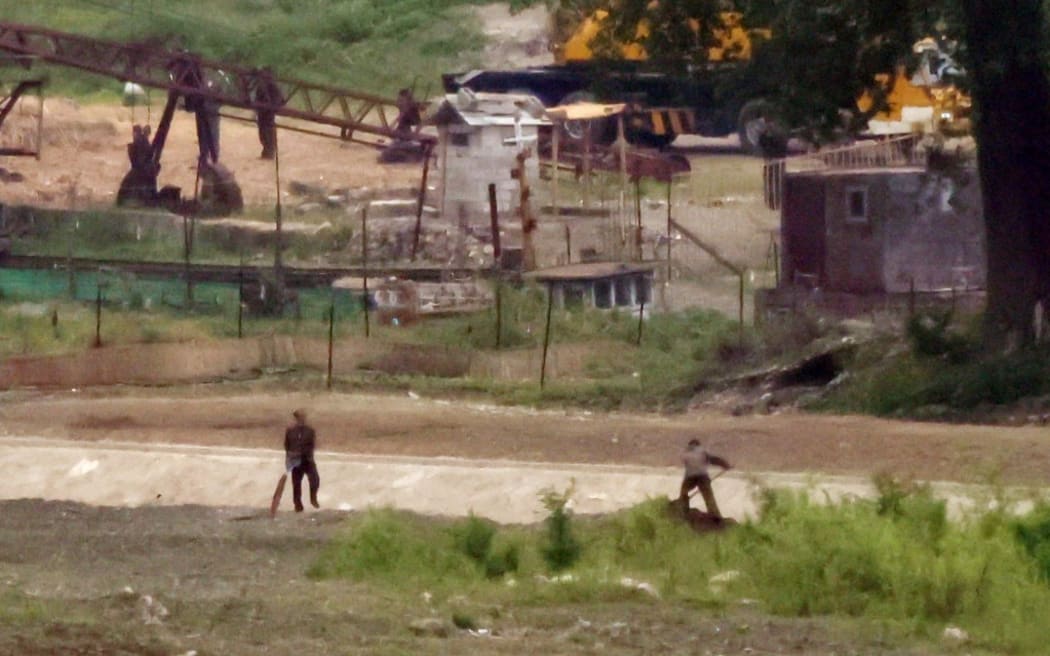People work in the North Korean town of Sinuiju, photographed from across the border in  Dandong, China in June 2023.
