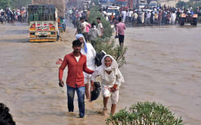 Commuters wade through a flooded national highway after river Kosi overflowed following heavy rains near Rampur in India's Uttar Pradesh state on October 20, 2021.