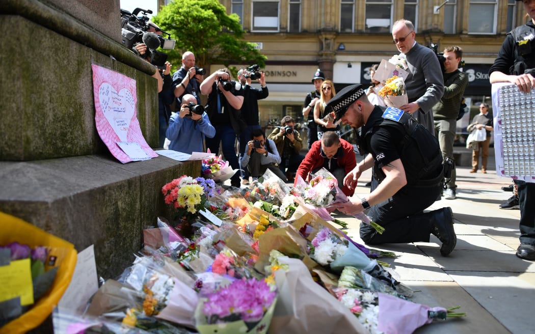 Police officers relocate floral tributes in St Ann's Square in Manchester following the attack at Manchester arena.