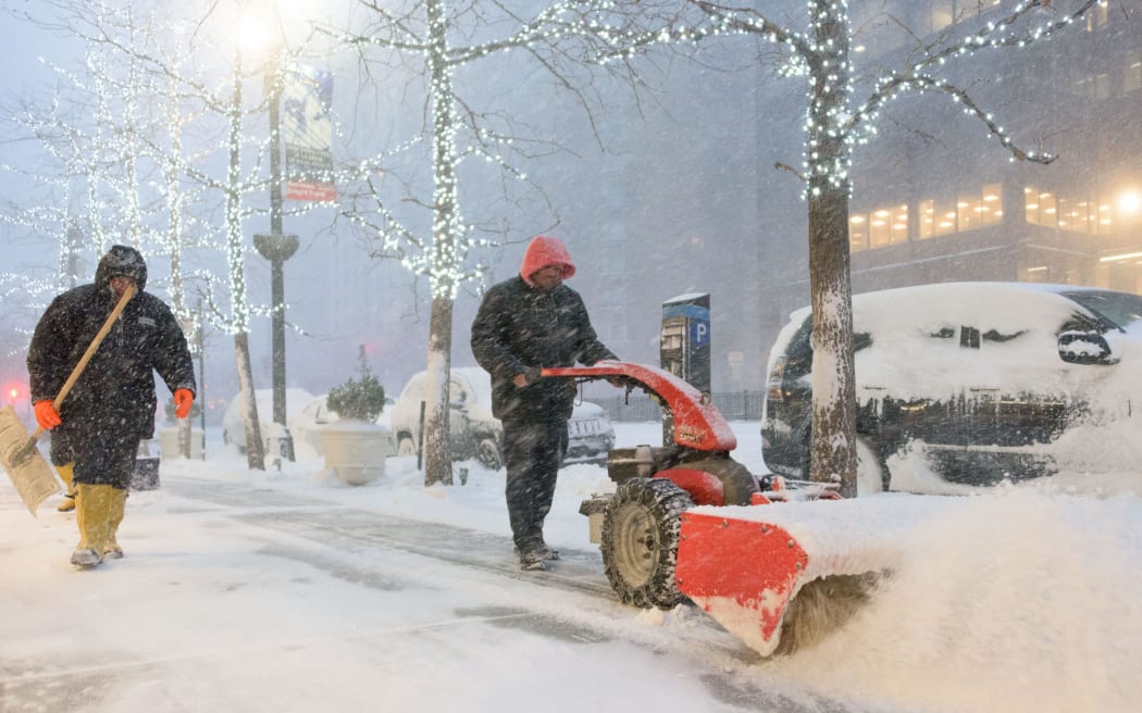Snow plough workers battle to clear pavements in New York. Public transport was being suspended and officials asked people to stay indoors.