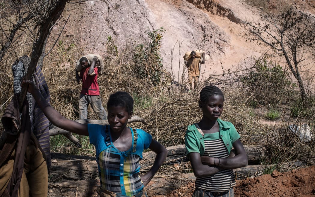 Women wait to receive mine waste material to separete cobalt from mud and rocks in a mine between Lubumbashi