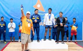 Marshall Islands weightlifter Patterson Raymon River at the podium (white shirt) is recognized by Majol2024 Micro Games Chairman Tony Muller for winning two gold medals and one silver medal Monday this week. Photo: Chewy Lin.