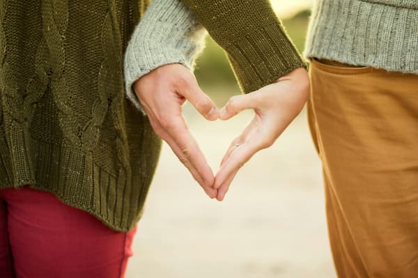 Couple linking hands to form a heart shape.
