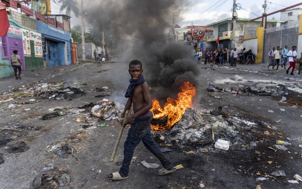 (FILES) In this file photo taken on October 10, 2022 a man walks past a burning barricade during a protest against Haitian Prime Minister Ariel Henry calling for his resignation, in Port-au-Prince, Haiti. - US officials on October 12, 2022 held talks in Haiti on requests for international intervention to combat spiraling insecurity but President Joe Biden's administration indicated reluctance over sending US troops. (Photo by Richard Pierrin / AFP)