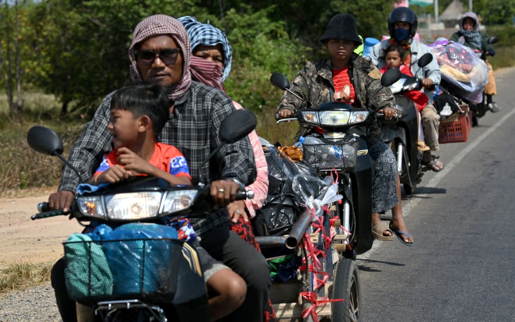Residents ride their motorbikes along a street after they evacuated following clashes along the Cambodia-Thailand border, in Siem Reap province on December 9, 2025.