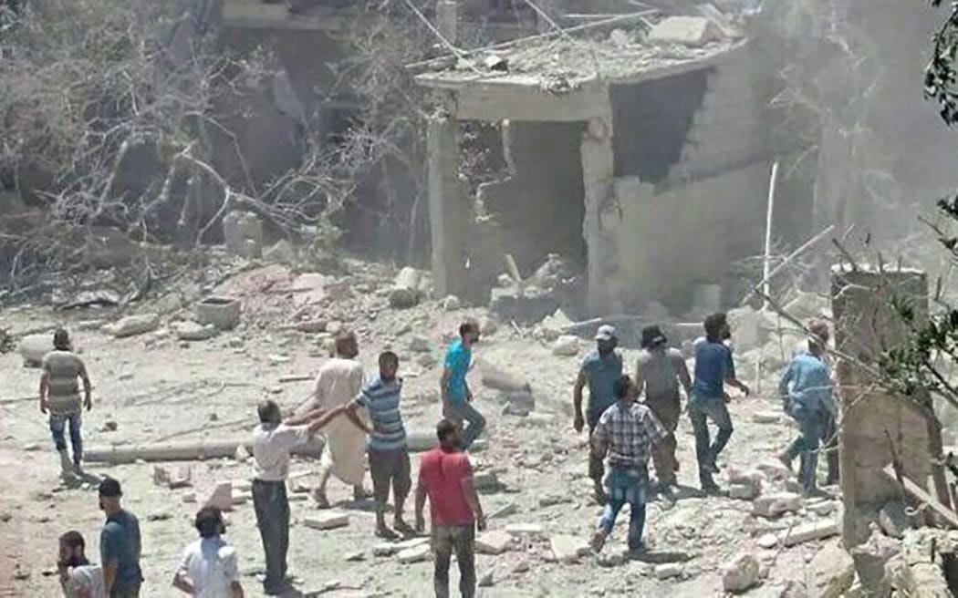 People gather around the area of a damaged building of a maternity hospital after it was hit by an air raid in the rebel-held town of Kafar Takharim.