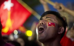 A supporter of Myanmar opposition leader Aung San Suu Kyi's party cheers as he watch a polling station count on a giant screen outside the party headquarters in Yangon.