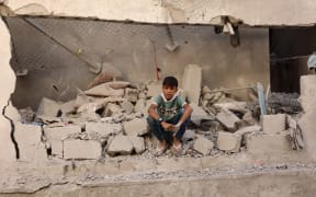 A Palestinian boy sits amongst the debris at the site of an Israeli strike on a school housing displaced Palestinians in Gaza City's Zaytoun neighbourhood on September 21, 2024. Gaza's civil defence agency said an Israeli strike on a school-turned-shelter in the Palestinian territory's largest city killed 19 people, while Israel's military said it targeted Hamas militants. (Photo by Omar AL-QATTAA / AFP)