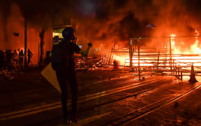 A protester walks before a barricade they set on fire in the Wan Chai district in Hong Kong on August 31, 2019. -