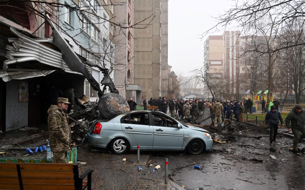 Military and onlookers stand at the site where a helicopter crashed near a kindergarten outside the capital Kyiv, killing Sixteen people, including two children and Ukrainian interior minister, on January 18, 2023, amid the Russian invasion of Ukraine. (Photo by Sergei Supinsky / AFP)