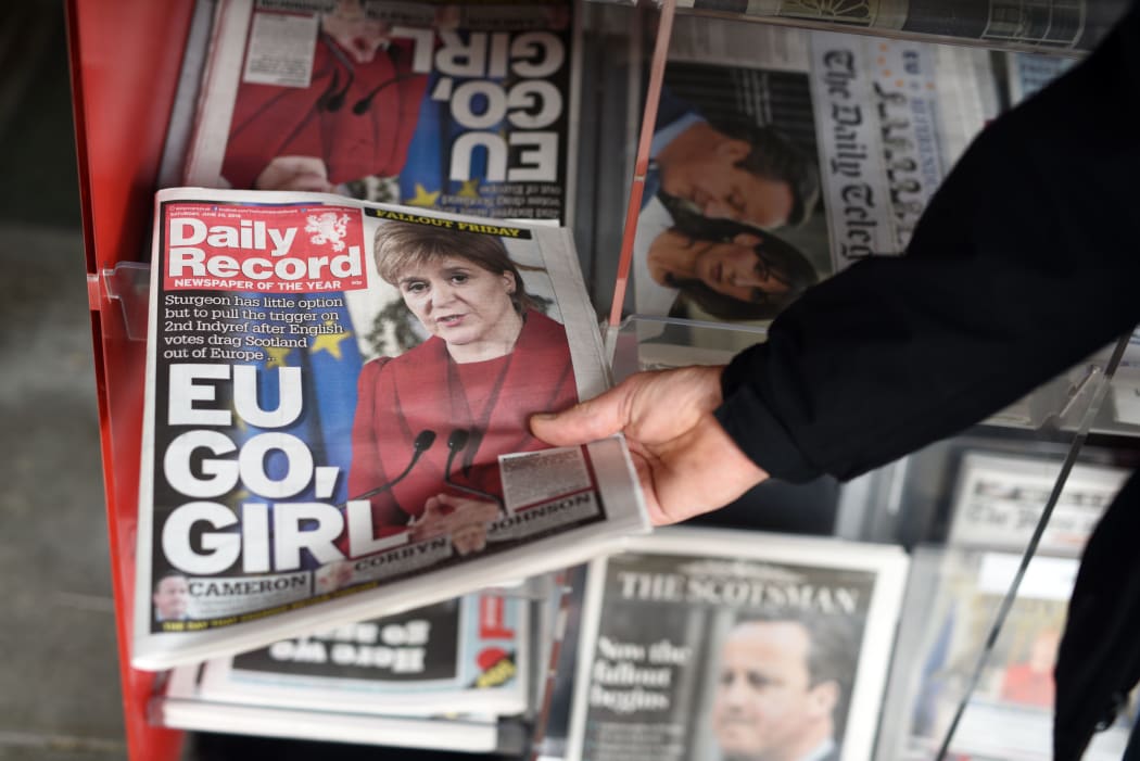 A man takes a copy of the Daily Record newspaper reporting on the pro-Brexit result of the UK's EU referendum vote and with an image of Scotland's First Minister and Leader of the Scottish National Party (SNP),