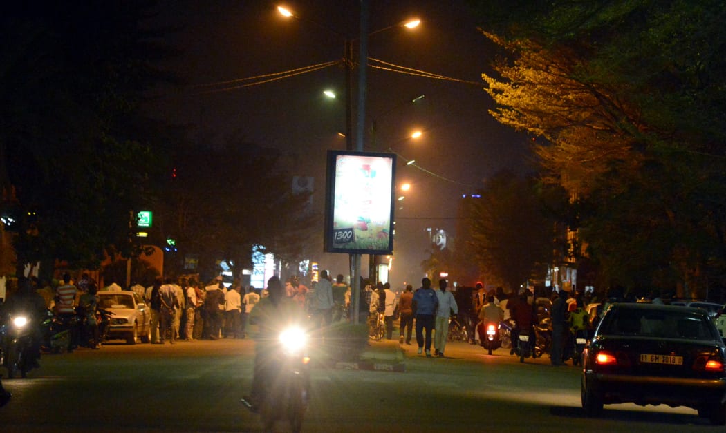 People gather on Kwame Nkruma avenue near Hotel Splendid as gunfire continues.