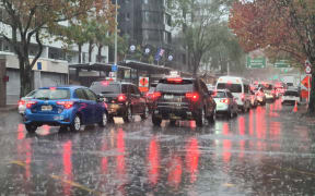 Cars drive through surface flooding in central Auckland as rain pelts the region on 9 May 2023.