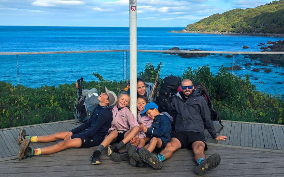 The Williams family sits near a sign at Stirling Point, Bluff, the end of the Te Araroa trail. 