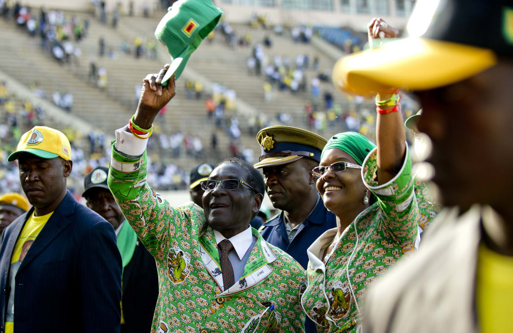 Zimbabwe's then-President Robert Mugabe (C) greets his supporters in Harare alongside his wife Grace after his address at a rally in Harare in July 2013.