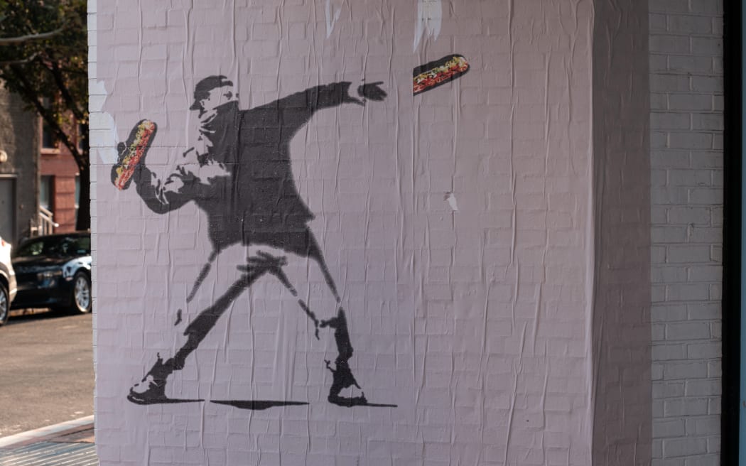 WASHINGTON, DC - AUGUST 31: Banksy-style posters depicting a protester throwing a sandwich at Secretary of Defense Pete Hegseth appear in the Georgetown neighborhood on August 31, 2025 in Washington, DC. The inspiration for the art, "Sandwich Guy" Sean Dunn has been charged with misdemeanor assault for hitting an ICE agent with a sandwich after a grand jury decided not to indict him on felony charges. The Trump administration has deployed federal officers and the National Guard to the District in order to place the DC Metropolitan Police Department under federal control and assist in crime prevention in the nation's capital.   Andrew Leyden/Getty Images/AFP (Photo by Andrew Leyden / GETTY IMAGES NORTH AMERICA / Getty Images via AFP)