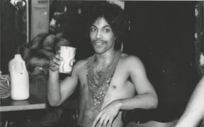 Prince sips some orange juice backstage during the Dirty Mind tour, 1981.