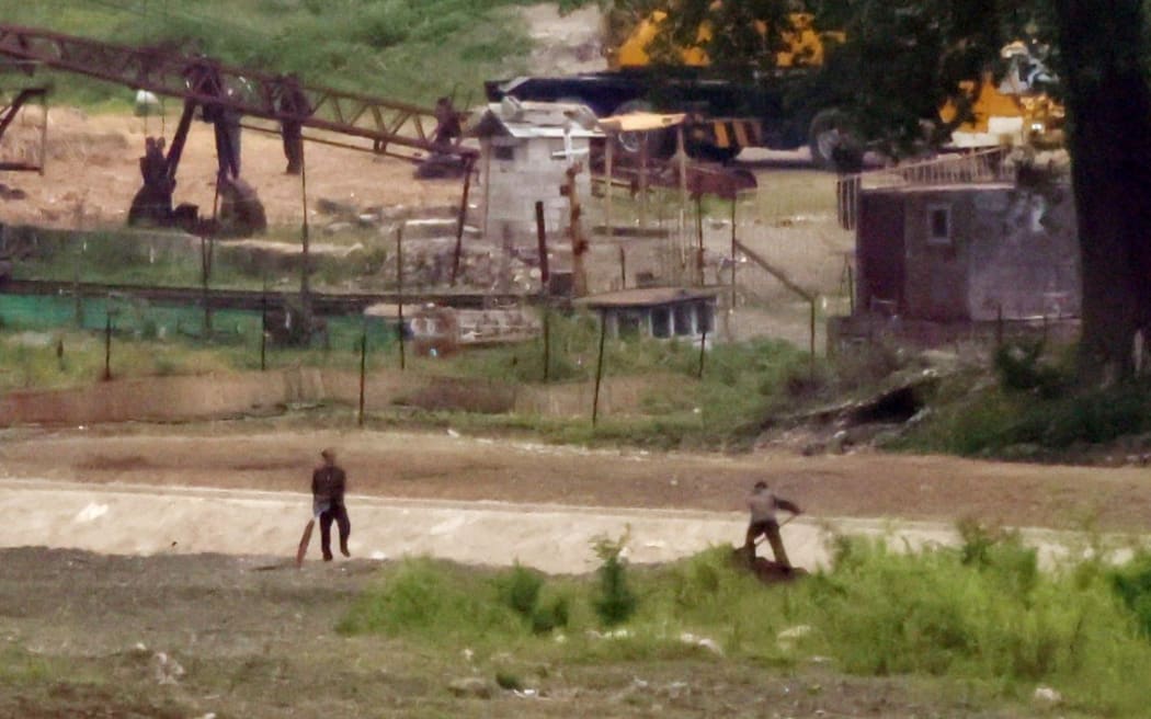 People work in the North Korean town of Sinuiju, photographed from across the border in  Dandong, China in June 2023.