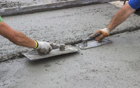 Leveling concrete with trowels, mason hands spreading poured concrete. Selective focus.