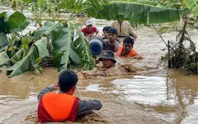 Residents are helped through high flood waters by police in Pyinmana town in Myanmar's Naypyidaw region on September 13, 2024, following heavy rains in the aftermath of Typhoon Yagi. Typhoon Yagi brought a colossal deluge of rain that has inundated a swathe of northern Vietnam, Laos, Thailand and Myanmar, triggering deadly landslides and widespread river flooding. (Photo by Sai Aung MAIN / AFP)