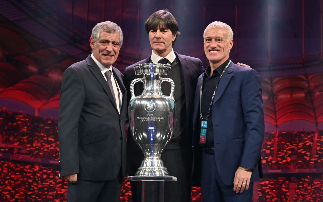 Coaches from Group F teams pose behind the trophy during the UEFA Euro 2020 football competition final draw in Bucharest on November 30, 2019 (L-R): head coach of Portugal Fernando Santos, head coach of Germany Joachim Loew and head coach of France Didier Deschamps.