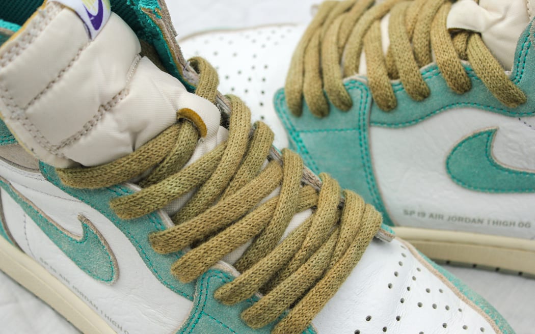 Close-up image of a pair of Nike Air Jordan 1 High OG sneakers. The shoes feature Jacob Smith's Wool-Lace, laces made from eco-dyed wool in a light brown shade.