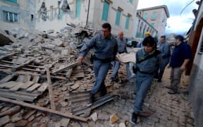 Rescuers carry a man from the rubble after a strong heartquake hit Amatrice on August 24, 2016.