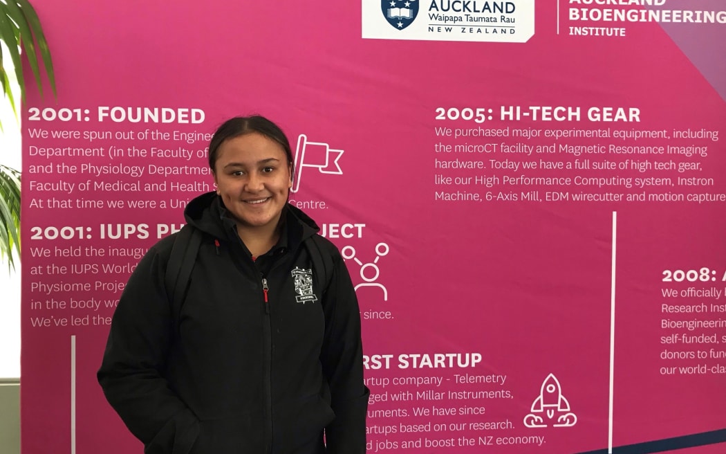 A young student stands in front of a pink and purple background that outlines the history of the ABI in white writing. Behind her we can see the headers2001: Founded and 2005: Hi-tech gear.