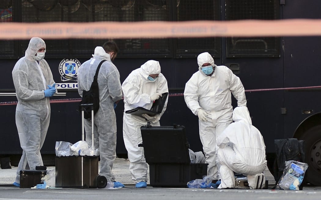 Police officers examine the entrance to the French embassy in central Athens, after two motorcyclists threw a hand granade and injured the guard, early on November 10, 2016.