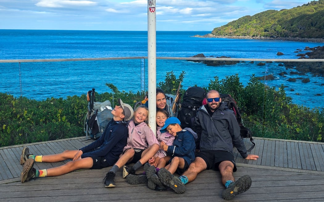 The Williams family sits near a sign at Stirling Point, Bluff, the end of the Te Araroa trail. 