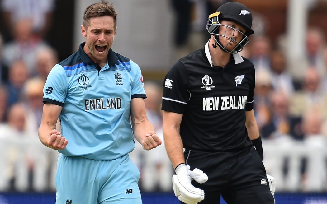 England's Chris Woakes (L) celebrates after taking the wicket of New Zealand's Martin Guptill for 19 runs during the 2019 Cricket World Cup final