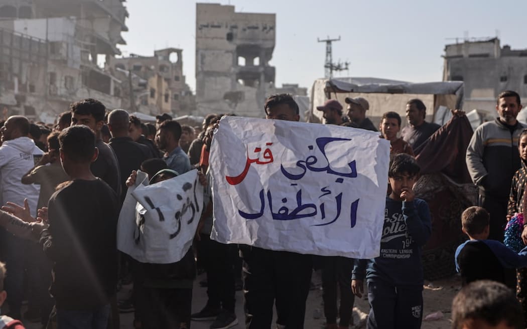 A man holds a sign that reads "Enough killing children" at a protest against Hamas.