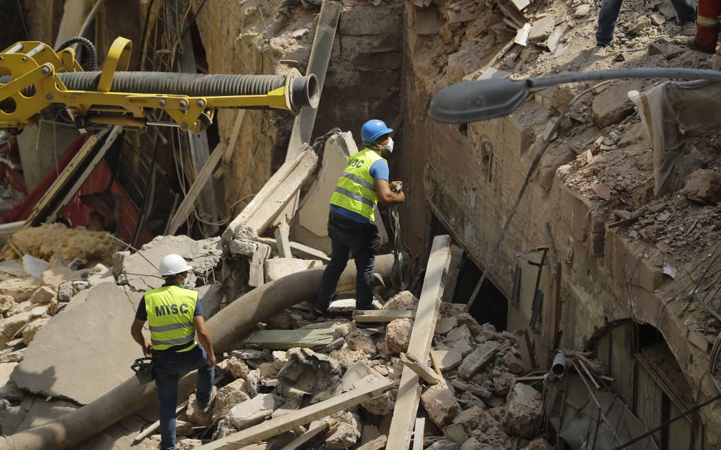 Rescue workers prepare to use a tube to vacuum debris from a badly damaged building in Lebanon's capital Beirut, in search of possible survivors from a mega-blast at the adjacent port one month ago, after scanners detected a pulse, on September 4, 2020. -