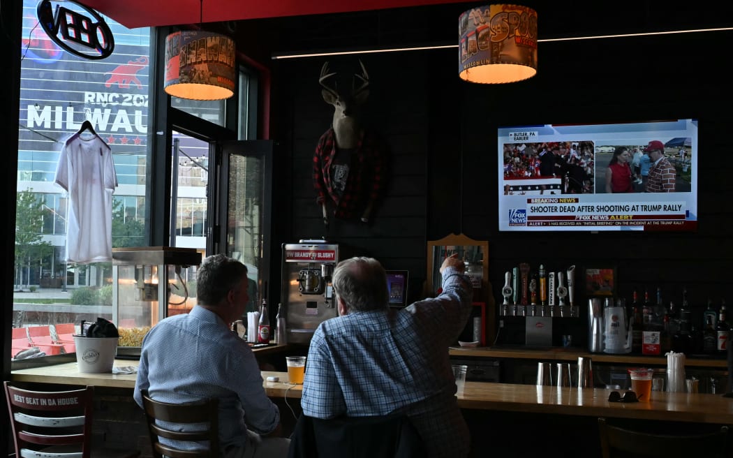 People watch the news on television in a bar in Milwaukee, Wisconsin, after hearing that Donald Trump was evacuated from the stage of his rally in Pennsylvania after shots were fired on 13 July, 2024.