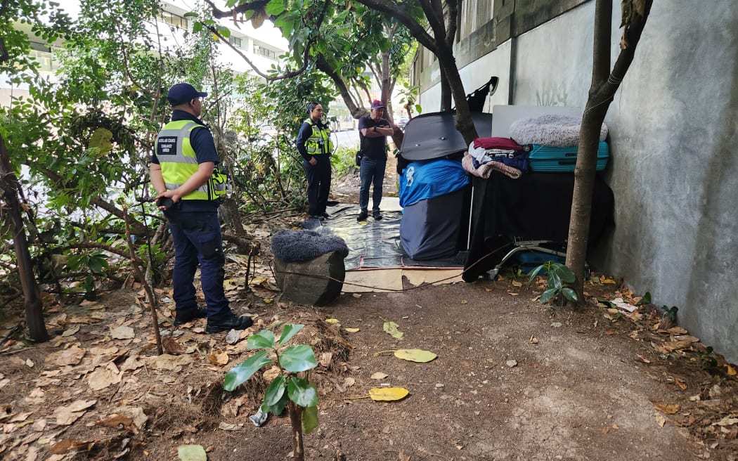 Auckland Council patrollers talk to rough sleepers in a makeshift shelter.