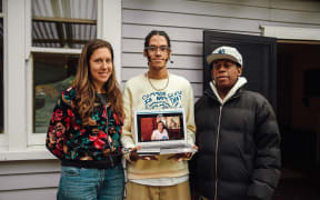 (L-R) Mara, Jamil, and Beto pose for a photo with Jamil holding a laptop where his sister Jazz is video calling in