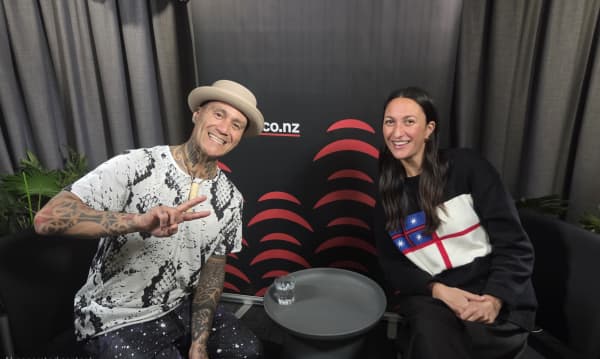 A smiling man and a smiling woman lean into a grey table.