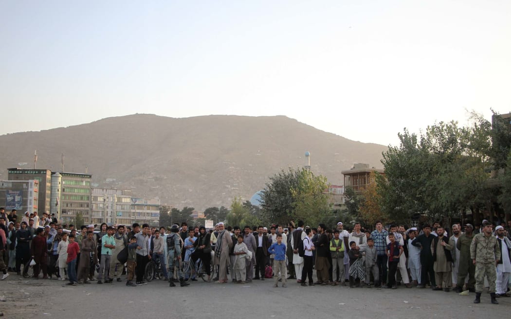 Afghan people are seen at the area after twin suicide blasts.