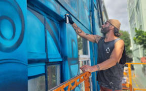 Raglan's Theo Arraj was working on a large-scale mural in Huatoki Plaza.