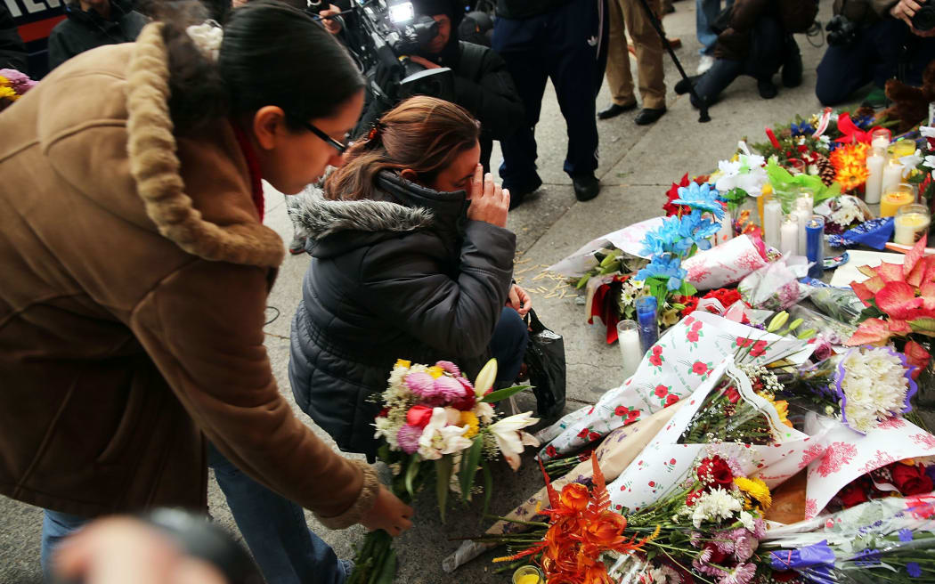 Women place flowers at a memorial to the two New York police officers shot and killed in the Bedford Stuyvesant neighborhood of Brooklyn.