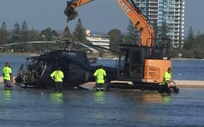 A day after the crash, airport workers prepare to remove a crashed helicopter that collided with another helicopter in Gold Coast on 2 January, 2023, killing four.