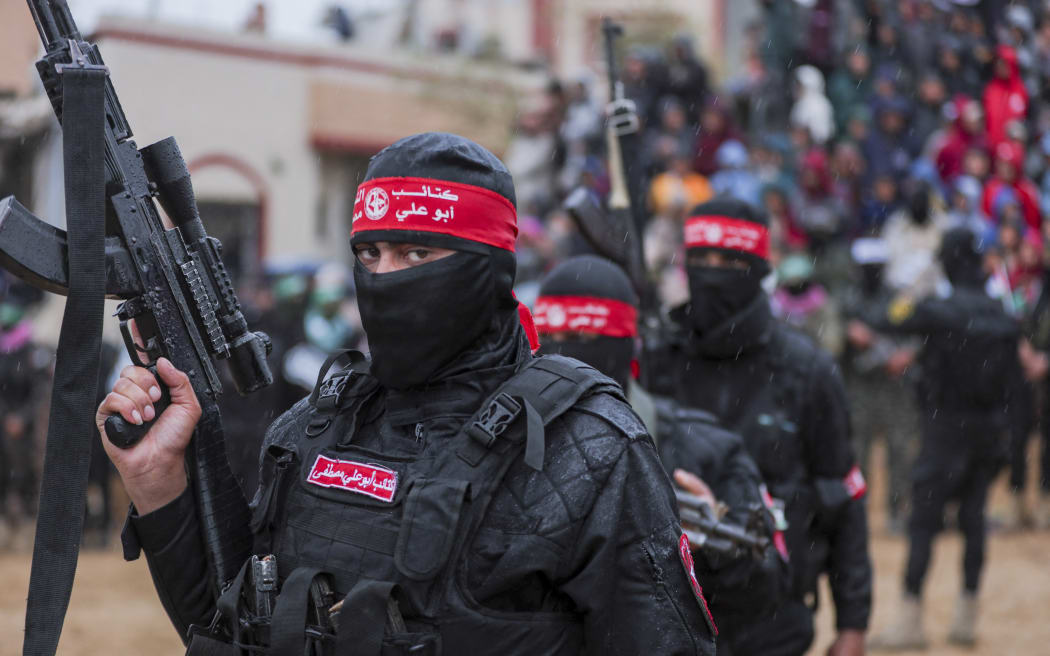 Palestinian Hamas militants gather at the site of the handing over of the bodies of four Israeli hostages in Khan Yunis in the southern Gaza on February 20, 2025. Hamas handed over the bodies of four hostages on February 20, including those of the Bibas family, who have become symbols of the hostage crisis that has gripped Israel since the Gaza war broke out. The transfer of the bodies is the first such handover of remains by Hamas since its October 7, 2023 attack on Israel triggered the war. (Photo by Abood Abusalama / Middle East Images / Middle East Images via AFP)