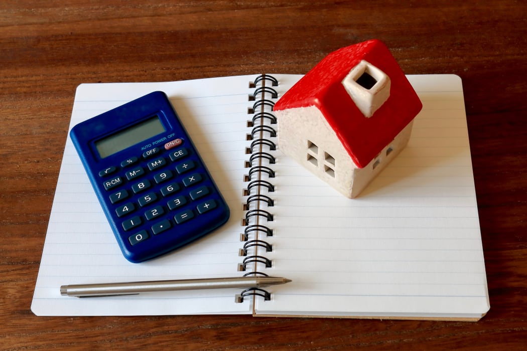 A calculator, a model of a house, a pen and a notebook - to illustrate financial planning and household budgets.